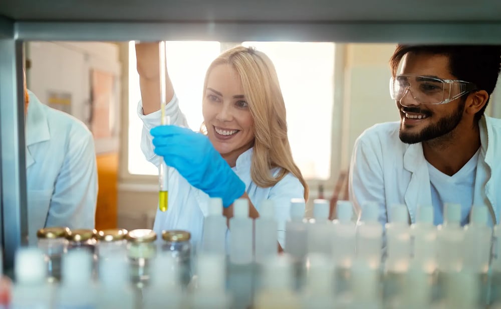 compounding-lab-technician-wearing-blue-gloves-lifting-test-tube-yellow-solution compounding-lab-technician-wearing-blue-gloves-lifting-test-tube-yellow-solution