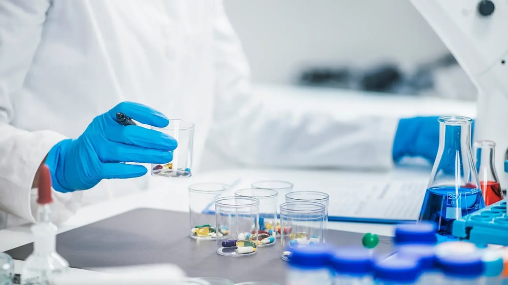 lab-technician-wearing-blue-gloves-sorting-capsules-and-tablets-into-sample-cups-in-pharmaceutical-testing-environment lab-technician-wearing-blue-gloves-sorting-capsules-and-tablets-into-sample-cups-in-pharmaceutical-testing-environment